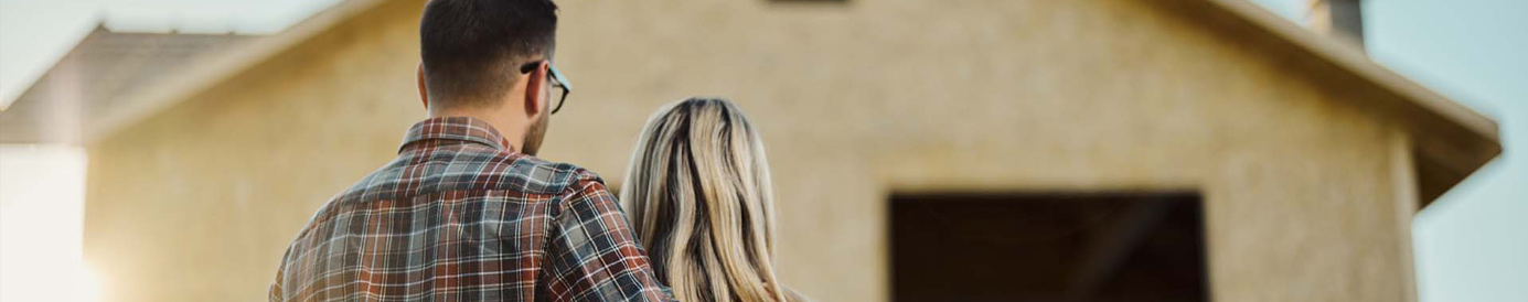 Una pareja de espaldas a la cámara mirando la reconstrucción de su casa.