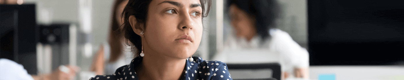 A woman sitting at a table in a coffee shop stares out of the window.